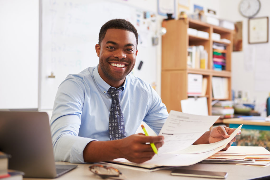 Portrait of African American male teacher working at desk - New England ...